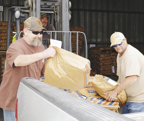 Tommy Wise brings a pallet of cattle feed to be unloaded by Lawerance Southerland, left, and Kelly Beaver Wednesday at the Farmers Co-Op in Clinton. CDN | Christian Jacobsen
