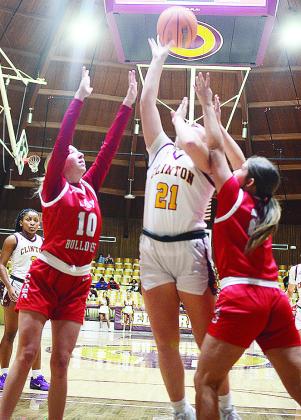 No. 21 Rhylee Rodebush goes up for a layup between two defenders during Clinton’s basketball home game Tuesday against Cache. Clinton’s Ethan Lofland takes a jump shot over a Cache defender during the Reds’ home game Tuesday against the Bulldogs.