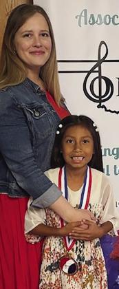 Piano instructor Danielle Shaw, left, stands with Adelyn Lonebear after she placed with a grading of a 1- from the Oklahoma Music Teachers Association (OMTA) State Achievement Auditions at the University of Oklahoma’s Catlett Music Center located in Norman.