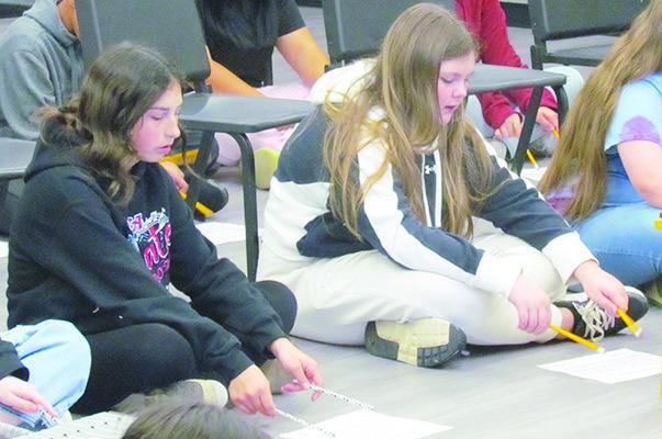 Leah Fanshier, left, and Ashlynn Gibson practice the song “Chicken on a Fencepost” on a paper xylophone before trying it on a real one at Clinton Middle School. CDN | Christian Jacobsen