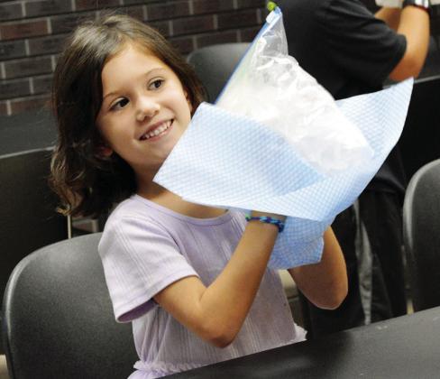 McKenzie Zraik swiftly shakes the bag of ice, salt, and cream to make soft-serve ice cream at the Clinton Public Library. CDN | Christian Jacobsen