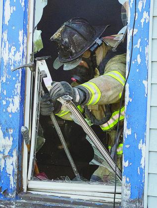 Clinton firefighter Bobby Winans busts the window out at the Mission House Saturday during training. CDN | Sam Goodwyn