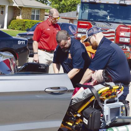 At about 4 p.m. Thursday Sinor EMTs Josh Steury, left, and Marcus Matthews work on a patient after a car crash at Modelle Avenue and S. 25th Street with Clinton Fire Chief Brett Russell in the background. Three individuals were transported to the hospital