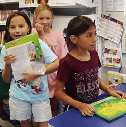 From left, Aubrey Carlson, Lily Leigh, and Giselle Torres check out books from the Western Plains Library’s Bookmobile Wednesday during Summer Playground at Washington Elementary. CDN | Christian Jacobsen
