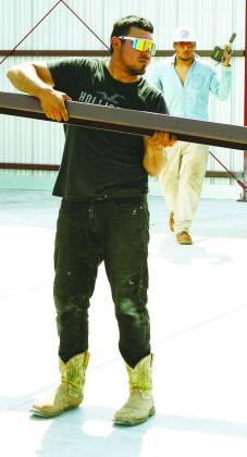 Jorge Polanco, left, and Aaron Rivera add crossbeams and frames to the T-hangar being built at Clinton Regional Airport. CDN | Christian Jacobsen