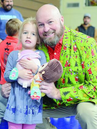 Scarlett Thomas, left, and Arapaho-Butler Public Schools Supt. Jay Edelen stand together after picking toys to take home from the Arapaho-Butler and Devon Energy Toy Express. CDN | Micah Ashcraft