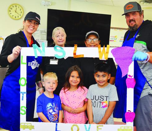 Front from left, Ezekiel Pointer, Paisley Hines, and Adrian Nava; back, Val Yoder, Bonnie Gray, Dolores Torres, and Jon Matthews stand together after the first lunch of National School Lunch Week at Nance Elementary School. CDN | Micah Ashcraft
