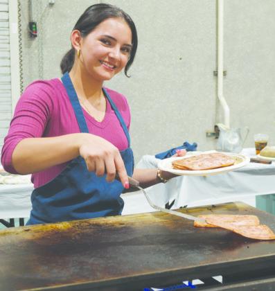 Clinton High School Key Club President Idalia Pelayo serves up some ham during the Kiwanis Pancake Day at the Frisco Center. CDN | Micah Ashcraft