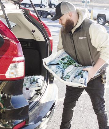 Thomas LaRocco loads a bag of ice melt into a customer’s car Wednesday in the parking lot of Sutherlands. CDN | Sam Goodwyn