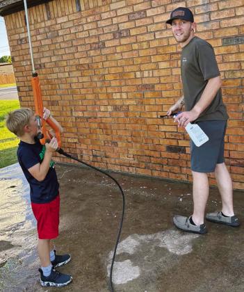 Timothy Sorter, left, is ready to finish pressure washing the walls of the Legion Field baseball concession stand with his dad Kyler Sorter at McLain Rogers Park. CDN | Courtesy photo