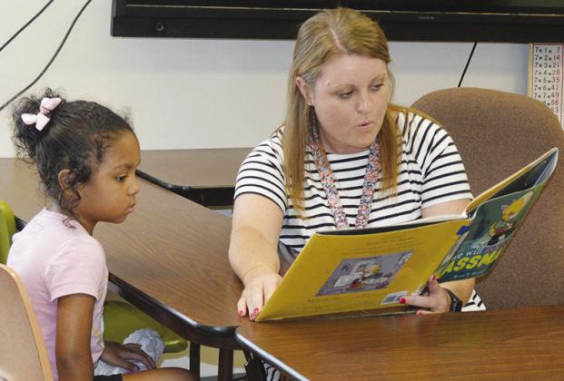 Adreena Sterling, left, is working on reading a book with Memory Proffitt from Multi-County Youth Services at Eastside Academy. CDN | Christian Jacobsen