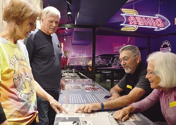 Oklahoma Route 66 Museum Director Pat Smith, left, and Virgil Smith show Stuart and Bevan Rogel from St. Petersburg, Fla., the price of some of the menu items from yesteryear at the museum’s diner exhibit area. CDN | Micah Ashcraft
