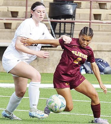 Clinton’s No. 2 Sammy Meraz fights a Heritage Hall defender for the ball during the Lady Reds’ home game Monday against the Lady Chargers. CDN | Sam Goodwyn
