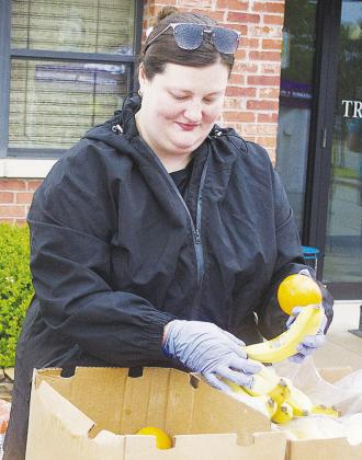Taylor Hamlin organizes fruit for the runners to eat on Frisco Avenue after completing the Clinton Classic Run. CDN | Sam Goodwyn