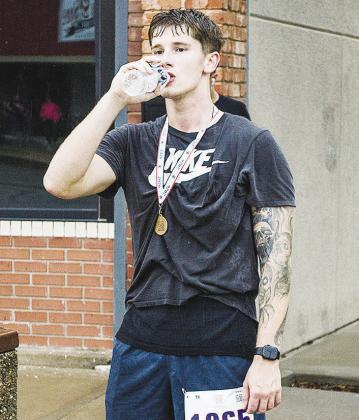 Bobby Winans drinks water on Frisco Avenue after finishing the 5K portion of the Clinton Classic Run.