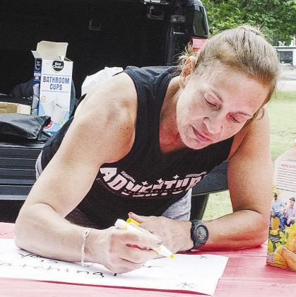 Tamara Thomas decorates a sign to encourage runners in McLain Rogers Park.