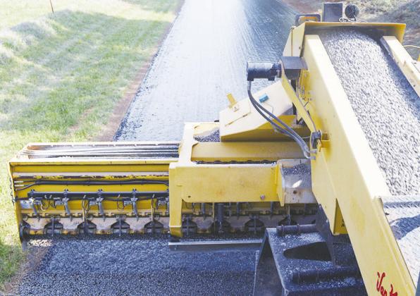 A Rock chipper spreads gravel on a layer of oil to become the first layer of a paved street at N. 2260 Road. CDN | Christian Jacobsen