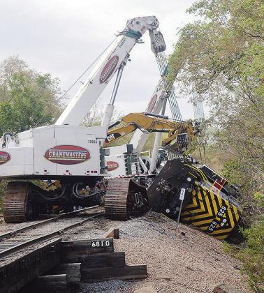 Cranes work Wednesday morning to reset this toppled locomotive on E. Modelle Avenue, behind Bar-S. CDN | Christian Jacobsen