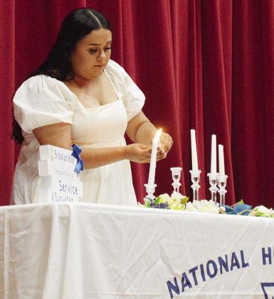Clinton National Honor Society President Vallery Desantiago lights the candle representing scholarship during the annual Clinton National Honor Society induction ceremony last week at the Clinton Middle School Auditorium. CDN | Micah Ashcraft