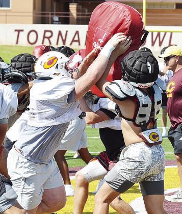 Clinton’s Brayden Fuller, left, pushes through the blocking pad held up by teammate Dyson Moss during practice in the Tornado Bowl. CDN | Sam Goodwyn