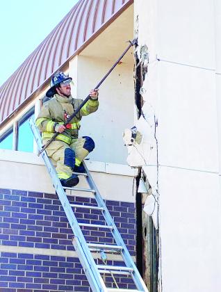Clinton Fire Department’s firefighter Alex Tyler works to clear debris while fighting a fire Saturday morning outside of the Clinton Public Library. CDN | Staff Photo