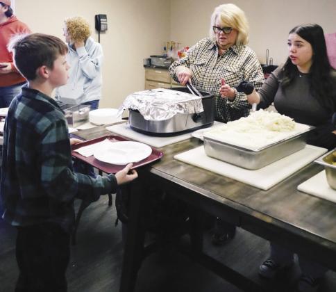 Tiernan Stevens, left, receives Thanksgiving food from Barbara Kreizenbeck, center, and Emma Swope at the annual Cornerstone Church Thanksgiving Feed. CDN | Emily Stephens