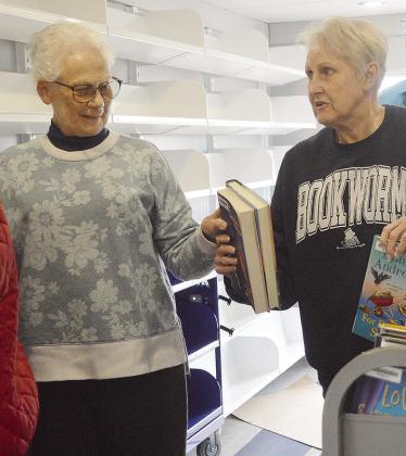 Western Plains Library System Board Members Carlotta England, left, and Kay Hagerman pass each other stacks of books while stocking the shelves of the new WPLS bookmobile. CDN | Micah Ashcraft
