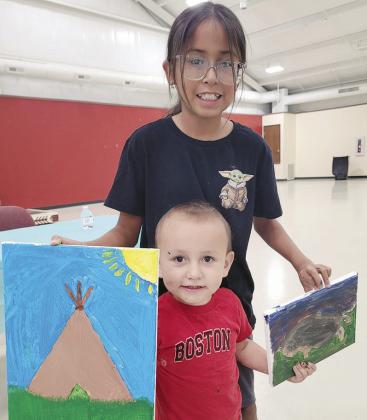 DJ Goodblanket, front, with Genevieve Goodblanket show off teepee pictures they painted during the Native Country Creative Arts paint party at the Cheyenne and Arapaho ERC Building.
