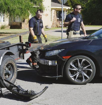 Clinton Firefighter Jacob Hoffman, left, and Lt. Billy Gerstenkorn remove the front bumper off a car so the user can drive it away after a twovehicle collision after 5 p.m. Tuesday on the corner of Modelle Avenue and Sixth Street. CDN | Christian Jacobsen
