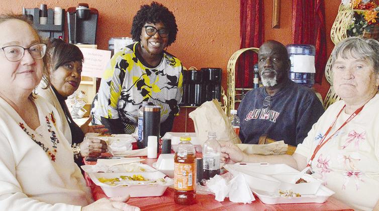 From left, Shelly Ramey, Gwen Bagby, H.O.S.T. Ministries Pastor Wilma Jackson, Lindell Brown, and Ethel Isbell break bread together during the recent H.O.S.T. Ministries community Christmas meal.