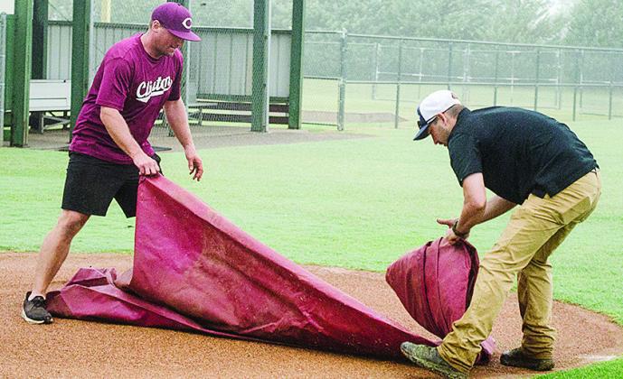 Rhett Blundell, left, and Lyndon Perry unroll a tarp to put on one of the fields at Schumacher Fields at Acme Brick Park Tuesday to protect it from the rain. CDN | Sam Goodwyn