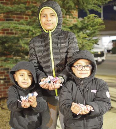 From left, Adriel Martinez, Sebastian Salas, and Eduardo Martinez show off their candy haul during the Clinton Festival of Lights Christmas Parade. CDN | Micah Ashcraft