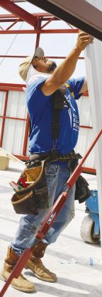 Jose Luise is helping install a metal panel to the inside frame of the new T-hangar being built at Clinton Regional Airport. CDN | Christian Jacobsen