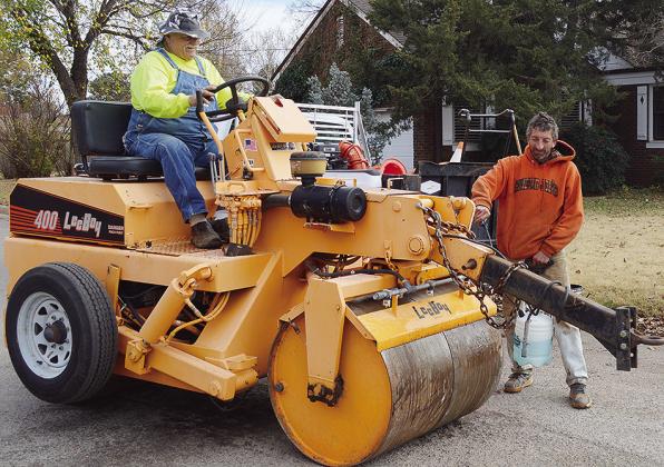 Mike Abramson, left, and Timothy Braecklein prepare a road roller to be used while fixing a pothole Wednesday afternoon at the intersection of 10th Street and Broadway Avenue. CDN | Micah Ashcraft