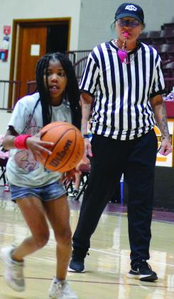 Naomi Hill, left, handles the ball as Jodi Crowdis watches and referees during the second-grade March Madness game at the Tornado Dome. CDN |Christian Jacobsen