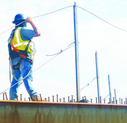 Eric Atilano feeds a steel safety cable through metal posts at the Interstate 40 construction over Neptune Drive. This safety cable is used to secure workers building the new bridge. CDN | Christian Jacobsen