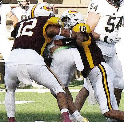 No. 12 Aaron Ramirez, left, and No. 10 JJ Ruiz combine to take down the Heritage Hall ball carrier during the Red Tornadoes’ season opener against the Chargers Friday in the Tornado Bowl. CDN | John Kinsey