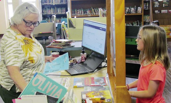 Mary Mahan, left, checks out Cohen Moore’s library books Tuesday at Southwest Elementary School. CDN | Christian Jacobsen