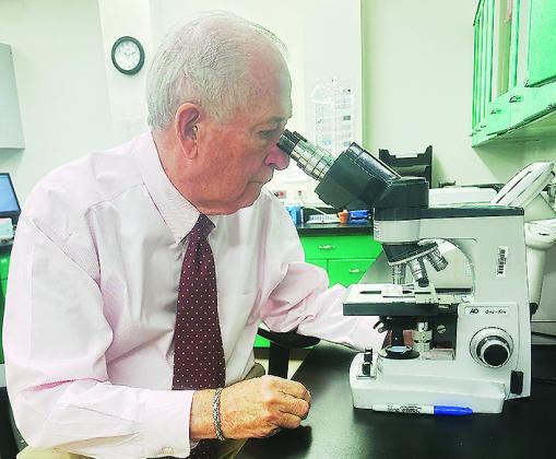 Dr. Raymond Cornelison examines a slide through a microscope in the Clinton Regional Hospital’s lab. CDN | Shiann Dawson