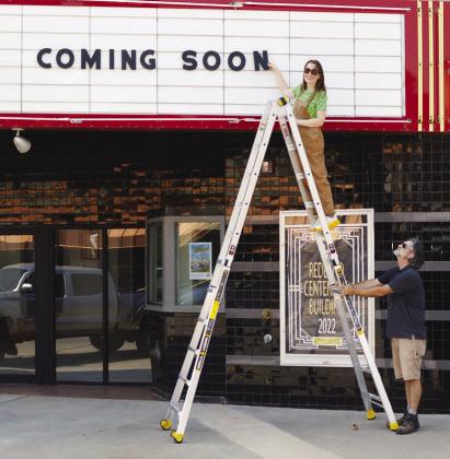 Natalie, left, and Ryan Houck are working on getting the Redland Theater up and running. Here they are adding a new message to the outside sign on Frisco Avenue. CDN | Christian Jacobsen