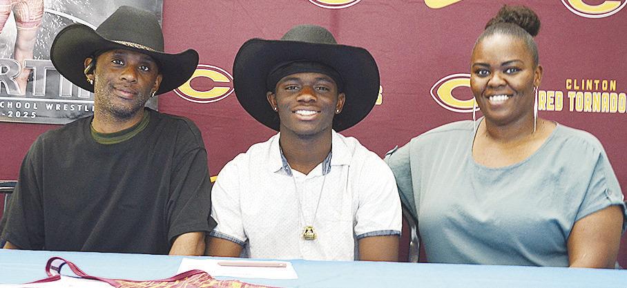Clinton’s Marquis Martin is all smiles as he celebrates signing to wrestle for Northeastern A&amp;M College in Miami with his father, Marquis Martin Sr., left, and his mother, Marcelle Martin, right. CDN | Sam Goodwyn