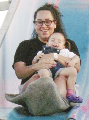 Vanessa Roque holds Nova Eaton as they slide down the Fun Slide at the Spring Carnival at Acme Brick Park. CDN | Christian Jacobsen