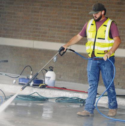 Maxwell Murray pressure washes new concrete Thursday at the Oklahoma Highway Patrol Troop H Headquarters construction site. CDN | Christian Jacobsen