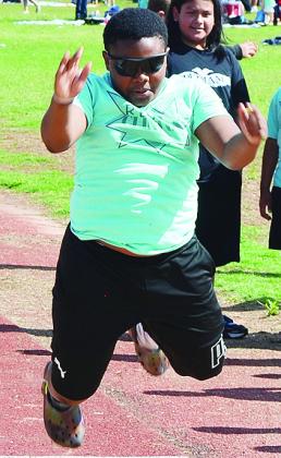 Clinton’s Jamarley Littleton leaps as far as he can in the long jump event as part of the Little Olympics to end the school year. CDN |Sam Goodwyn