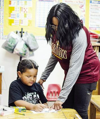 Khalil Douglas, left, gets help from Tosha Jones on a coloring book of Martin Luther King Jr. to celebrate Black History Month at Eastside Academy. CDN | Sam Goodwyn