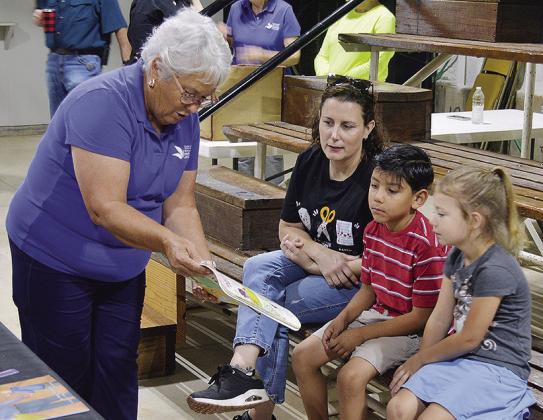From left, Paula Sawatzky of the Women’s Leadership Committee helps inform WOCS kindergarten teacher Danyal Walters along with students Abdiel Botello and Avery Nickel where their food from their lunchboxes and school meals come from Friday morning at the Custer County Free Fair. CDN | Christian Jacobsen