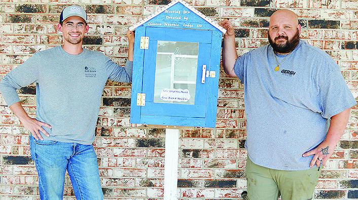 Clinton Masonic Lodge members Cadence Richeson, left, and Jason McDow set up a blessing box just outside of United Supermarket. People may take items if needed and donate as well. CDN | Micah Ashcraft