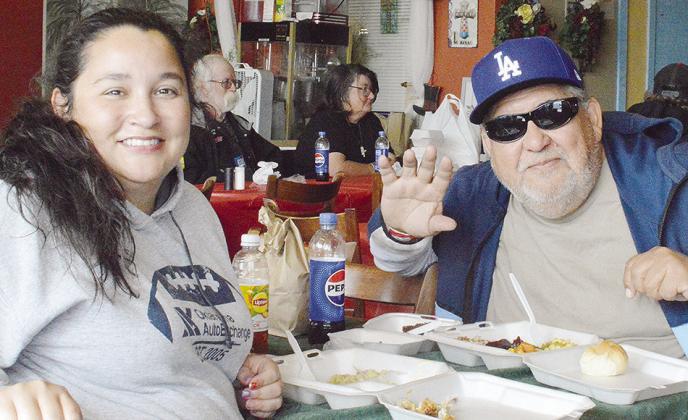 Jessica Maldonado, left, and Roy Estraca enjoy a festive time together during the recent H.O.S.T. Ministries community Christmas meal. CDN | Micah Ashcraft