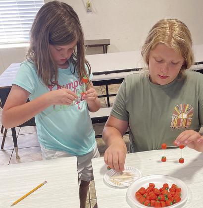Western Oklahoma Christian School 4-H members Emily Chupp, left, and Darcy Funk build a candy pumpkin toothpick tower during the club’s October meeting.