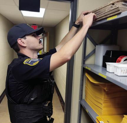 Ofc. Brady Bridges retrieves an evidence box while preparing to file a report at the Clinton Police Department. CDN | Shiann Dawson